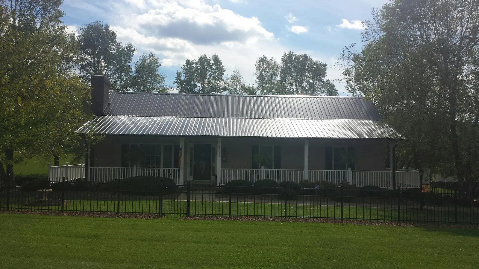 Gray metal roof on a brick ranch with a full width front porch — Gutter Guard Installation work by our crew in Plattsburgh